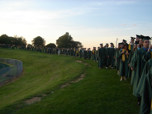 a group of people in graduation robes standing near grass