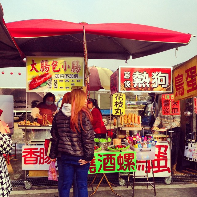 women at outdoor market looking around and selling food