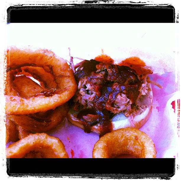 a meat filled sandwich on top of some onion rings