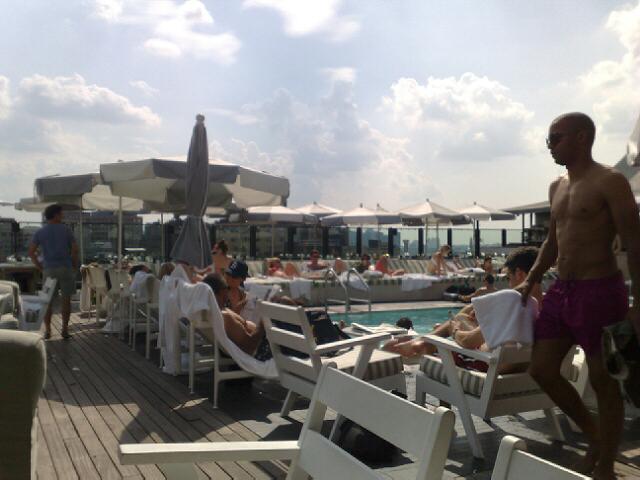 several people sunbathe on a deck with chairs and tables