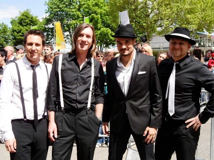 a group of young men standing next to each other in black tuxedos