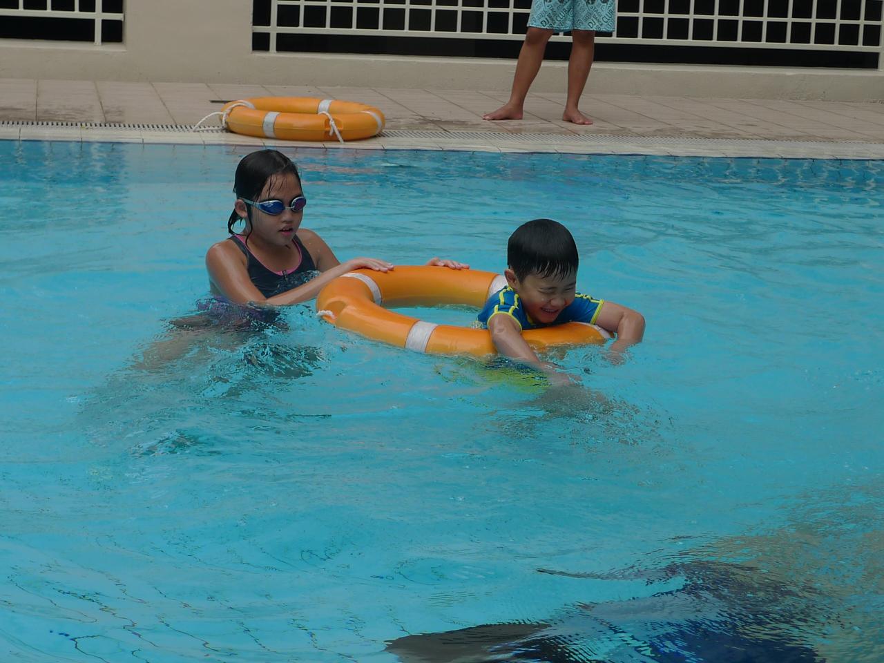 children in a pool playing with inflatable swimming rafts