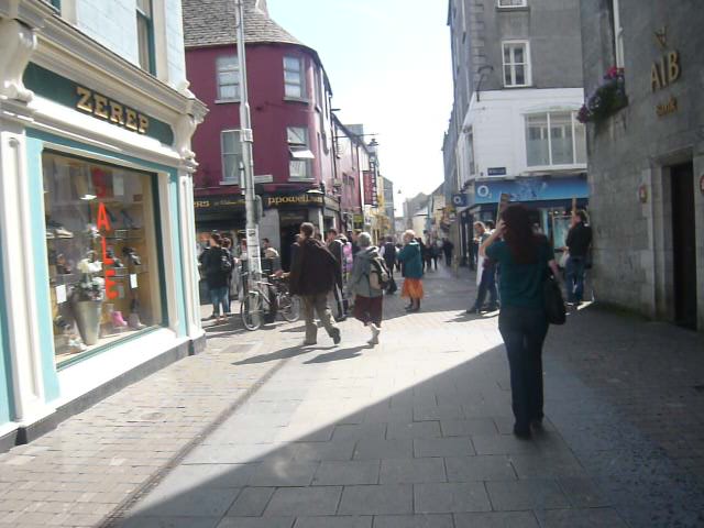 people walking down a street in front of shops