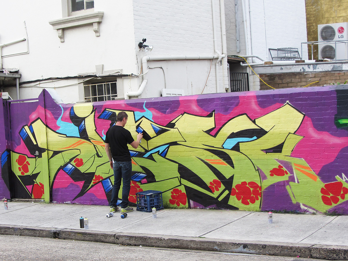 a young man painting a graffiti on a wall
