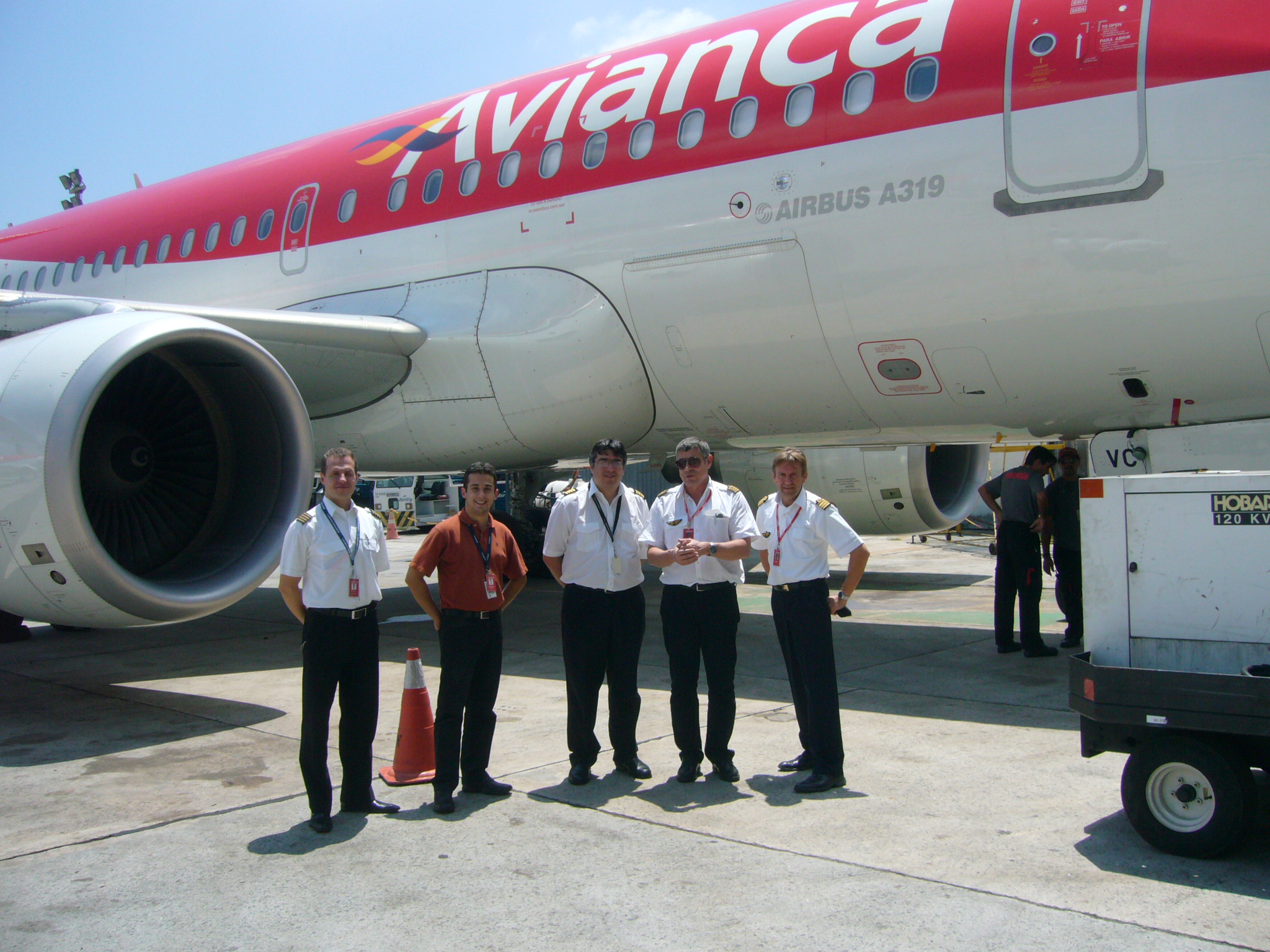 several pilots standing in front of an airplane on the tarmac