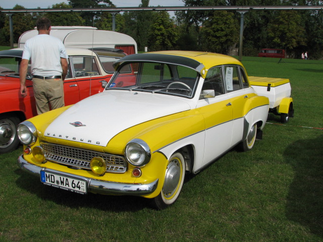 a yellow and white car sitting in the grass