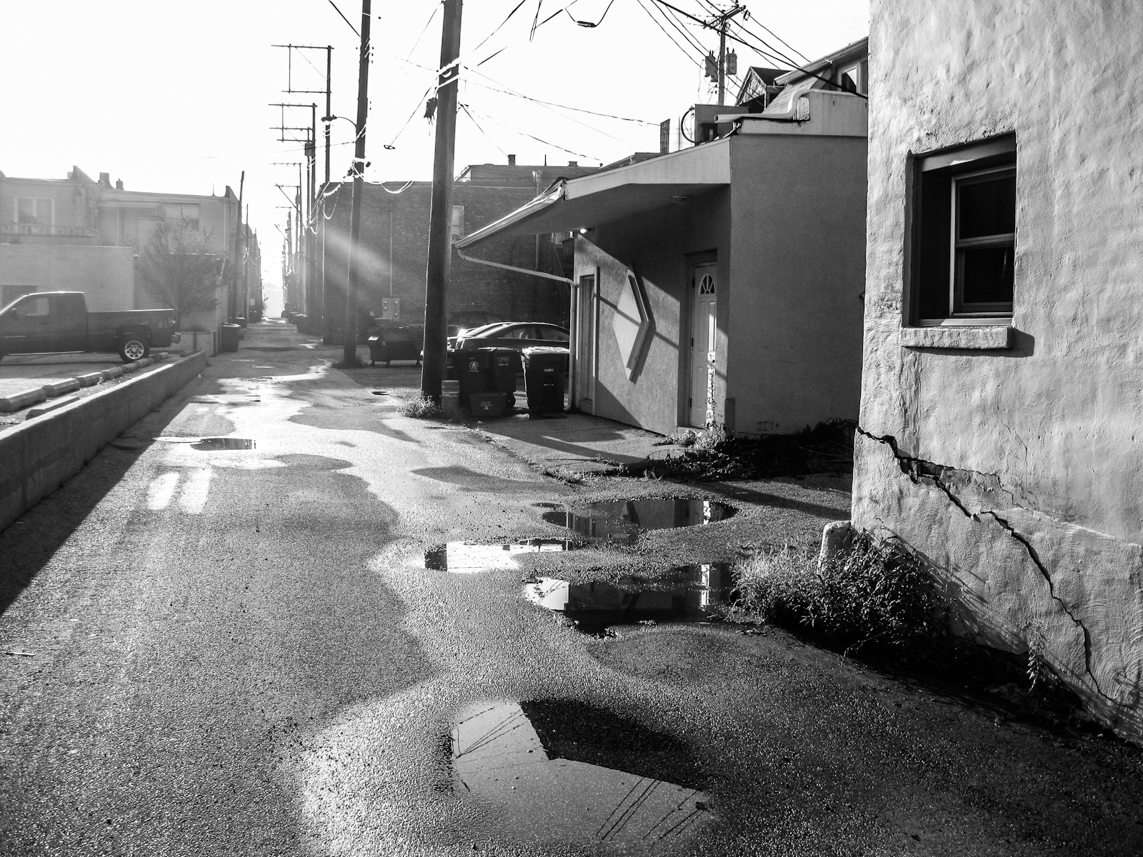 a black and white po of an alley with broken pipes