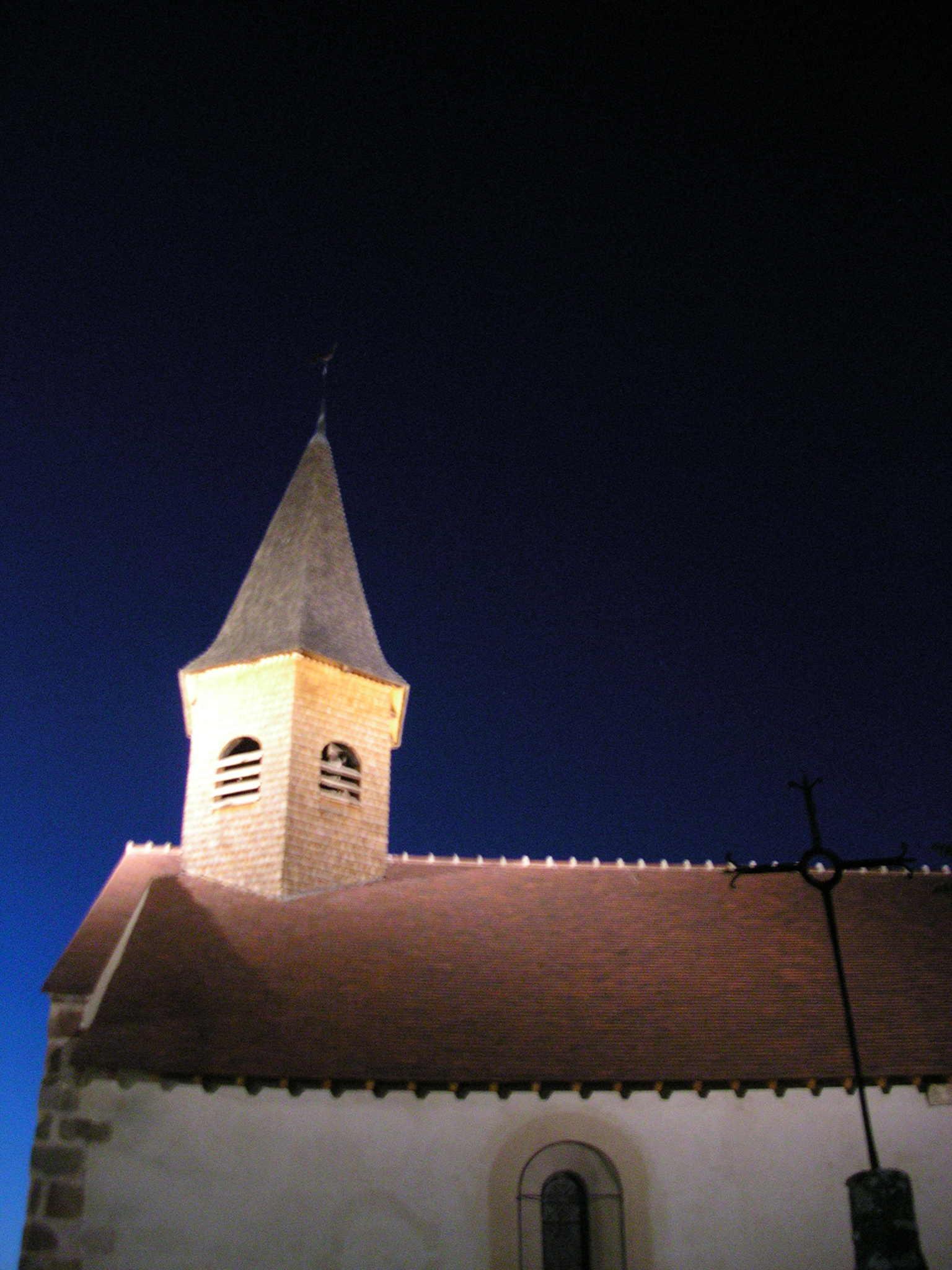 a clock tower is illuminated at night near a church