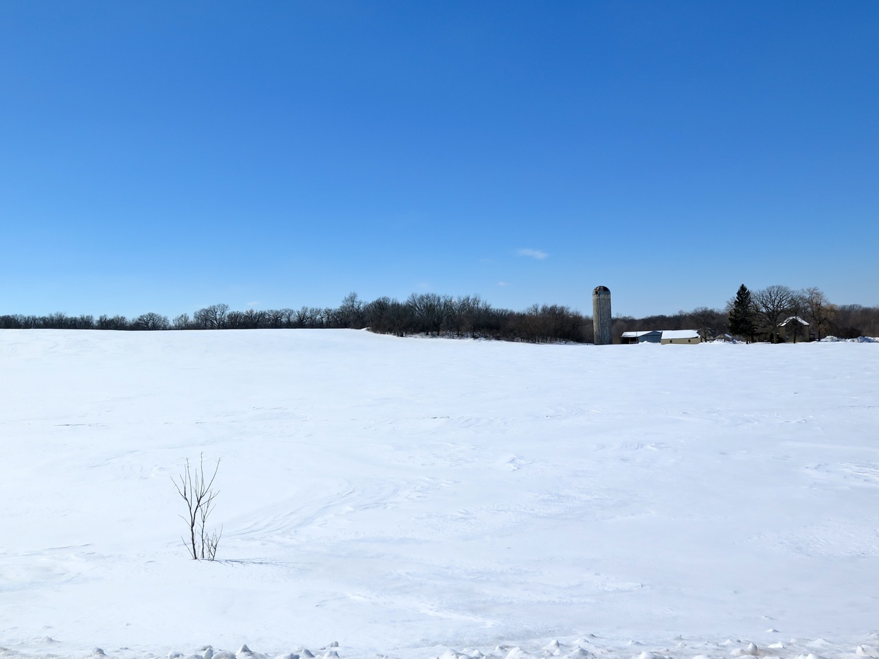 a field covered in snow and a big blue sky