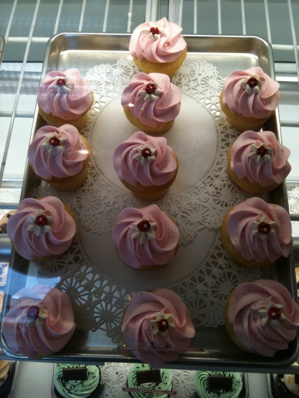 cupcakes with pink frosting sitting on top of a cake pan
