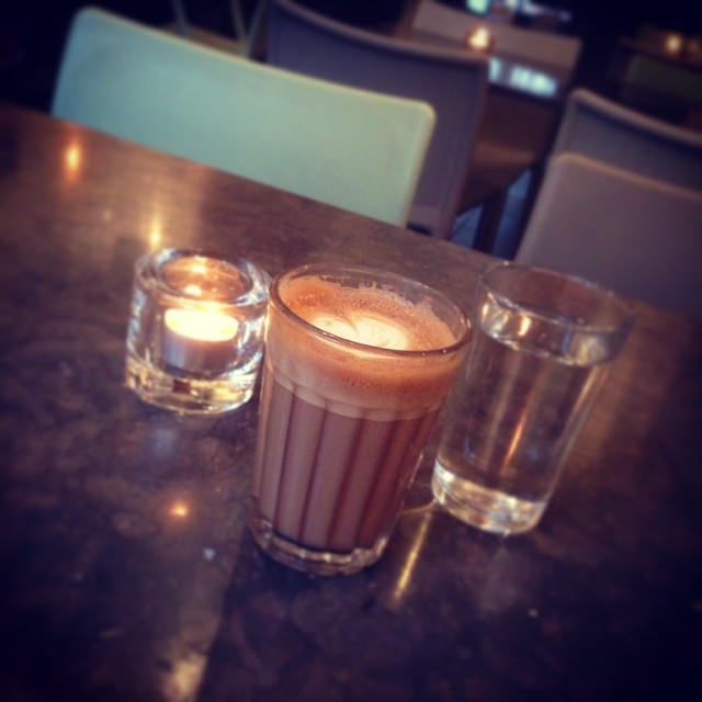 two glasses with drinks sitting on top of a table