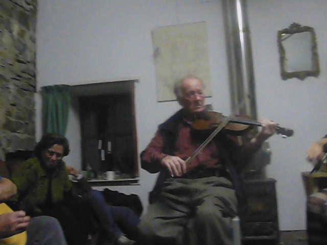 a man playing an old fashioned violin in a living room