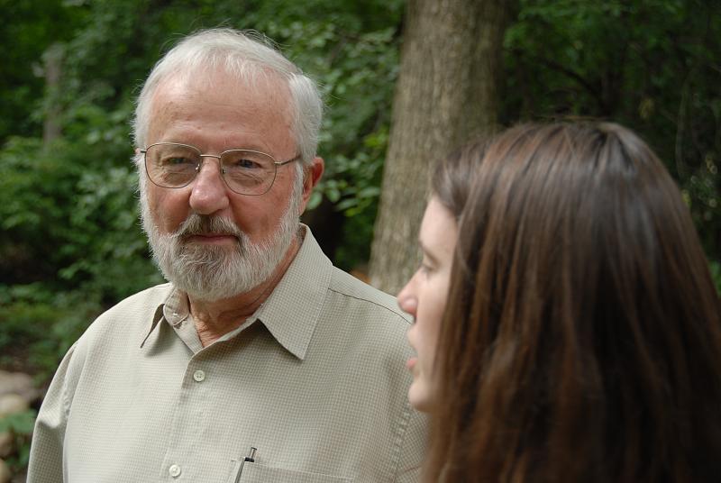 a man and a woman are talking near a forest