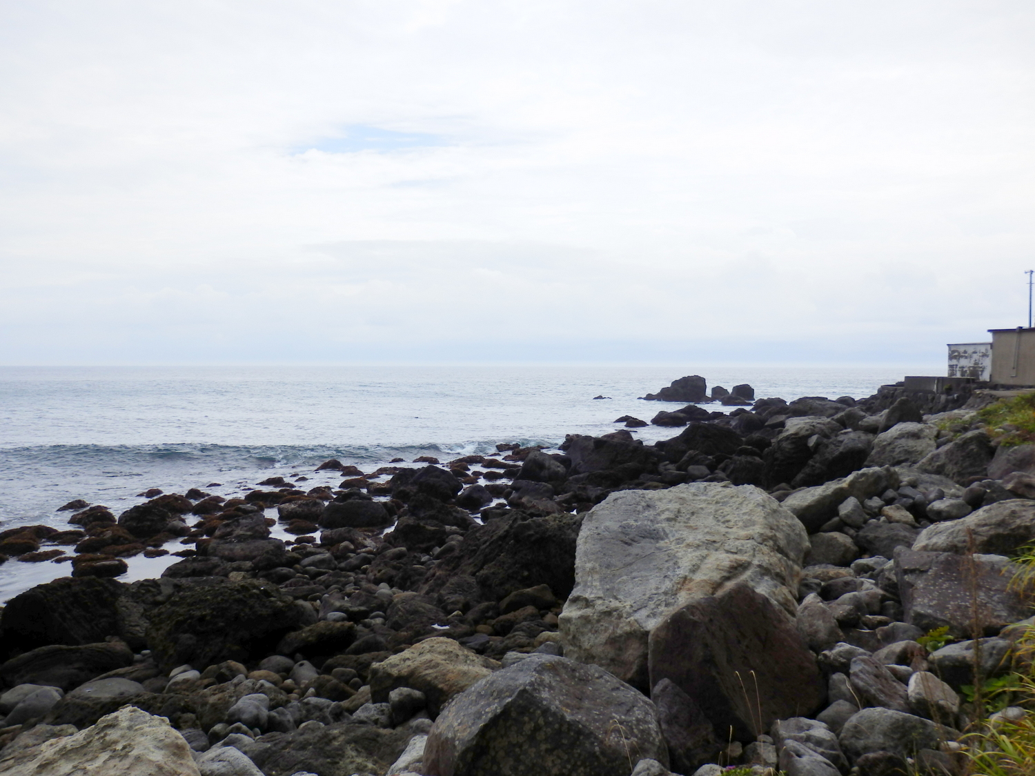 an empty ocean with a rock formation on the beach