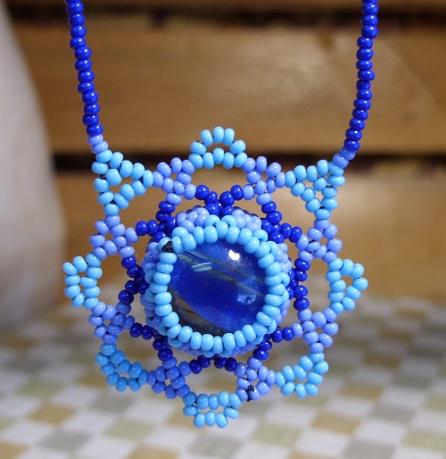 a necklace with a blue beaded design and a small blue glass bead piece