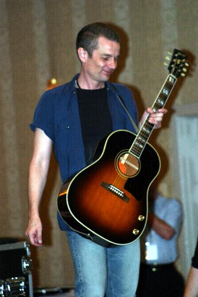 man holding a guitar while standing on stage