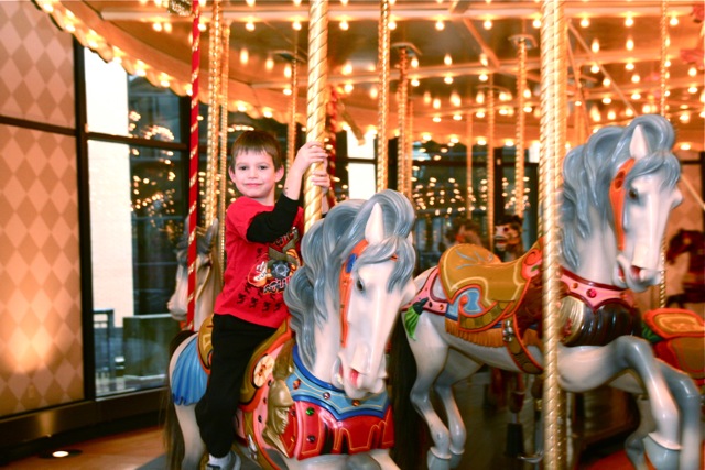 a  riding on the front of a merry go round horse