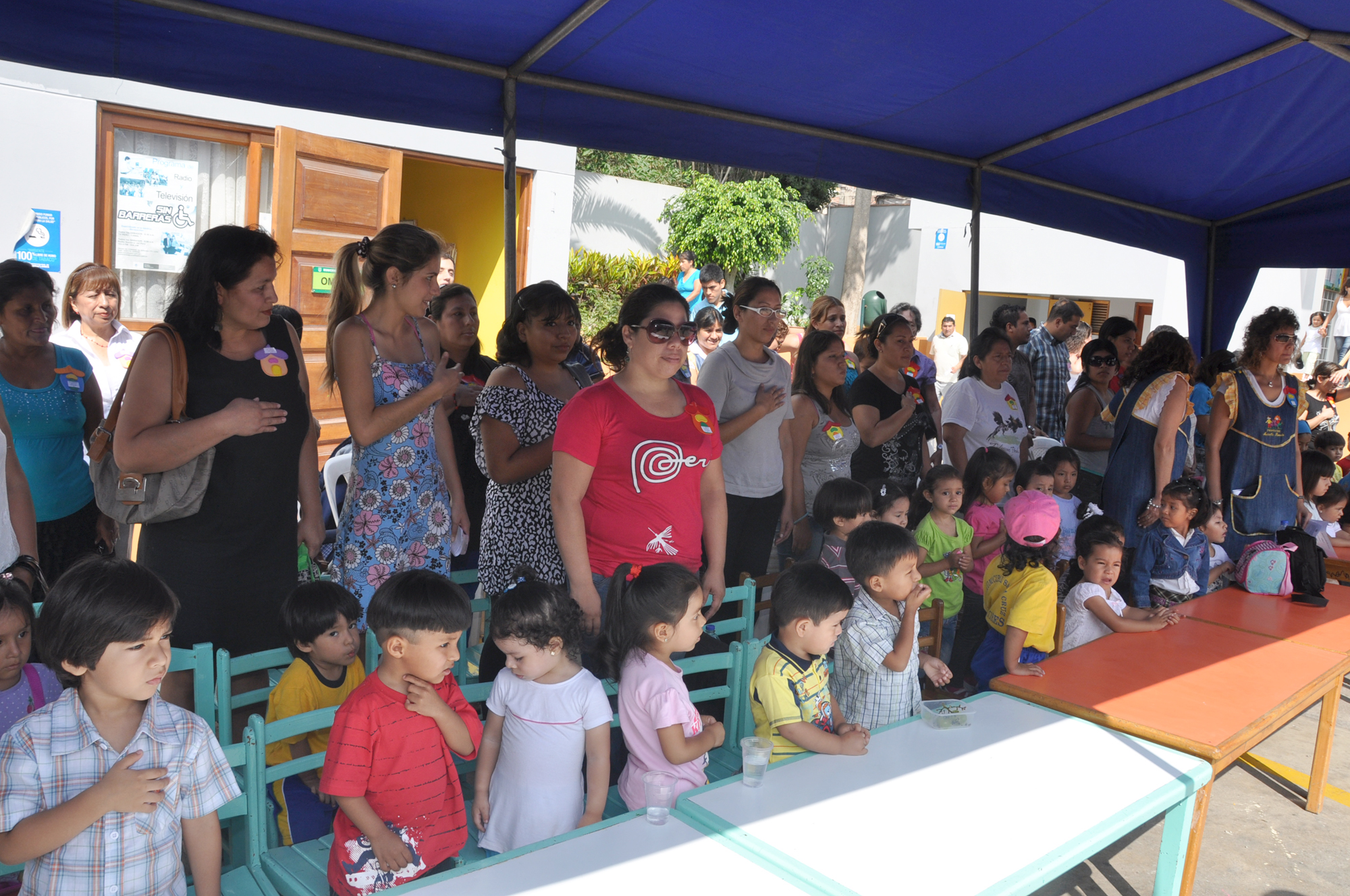 a crowd of people standing around a table with children