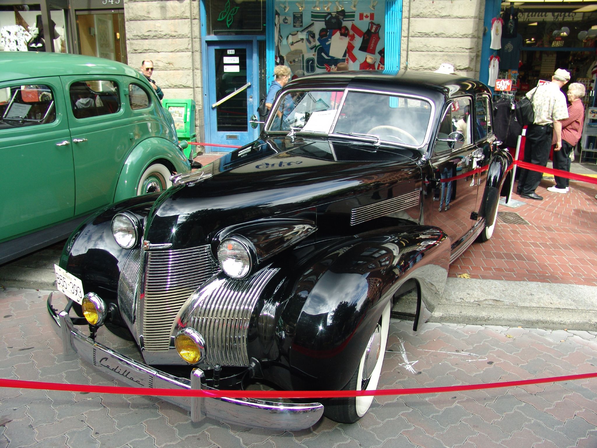 an old fashioned car parked on the street in front of some other vehicles