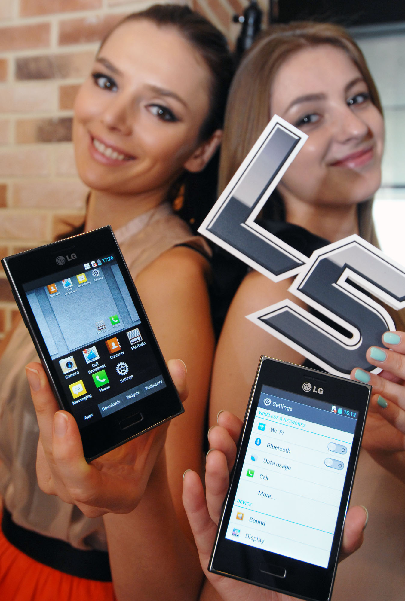 two girls showing off their cell phones that each have a logo