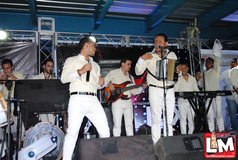 some men in white on stage with instruments and one is singing