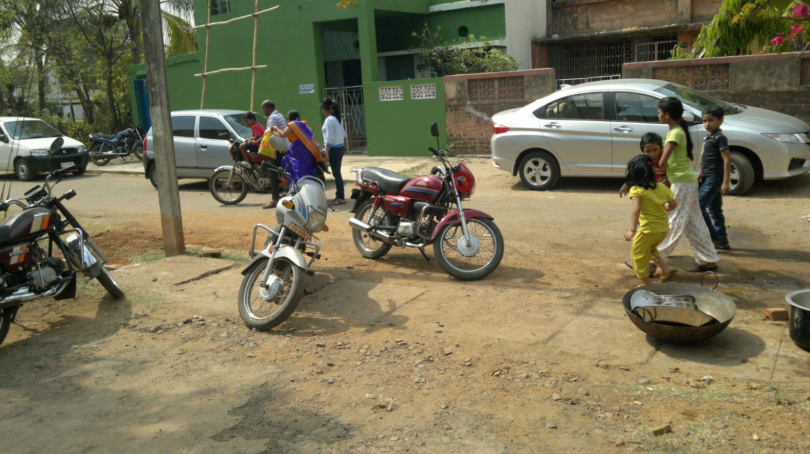 people stand around several motorcycles in the street