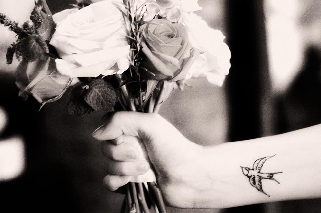 a woman with a tattoo on her arm holding a bouquet of roses