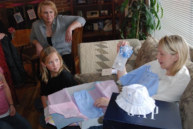 a woman in grey shirt looking at several children holding clothes