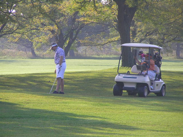 a man golfing with a few people standing around in the distance