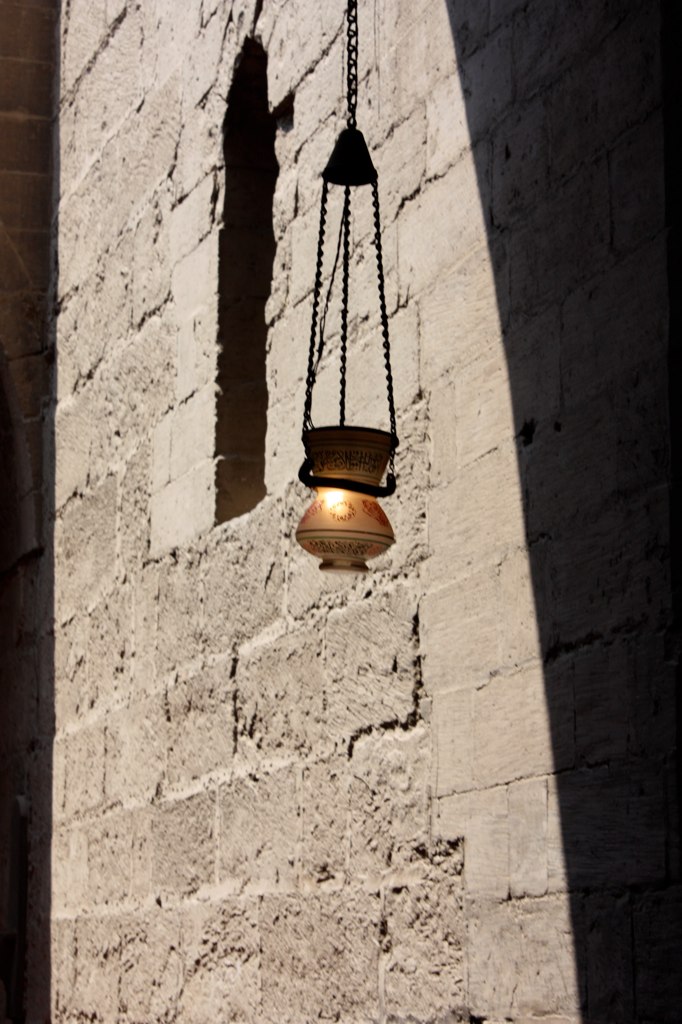 an old hanging light fixture near the shadow of another wall