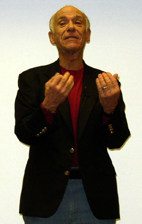 a man in a black blazer is holding his hands together