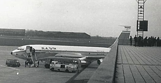 an airplane on a runway and some cars parked near it