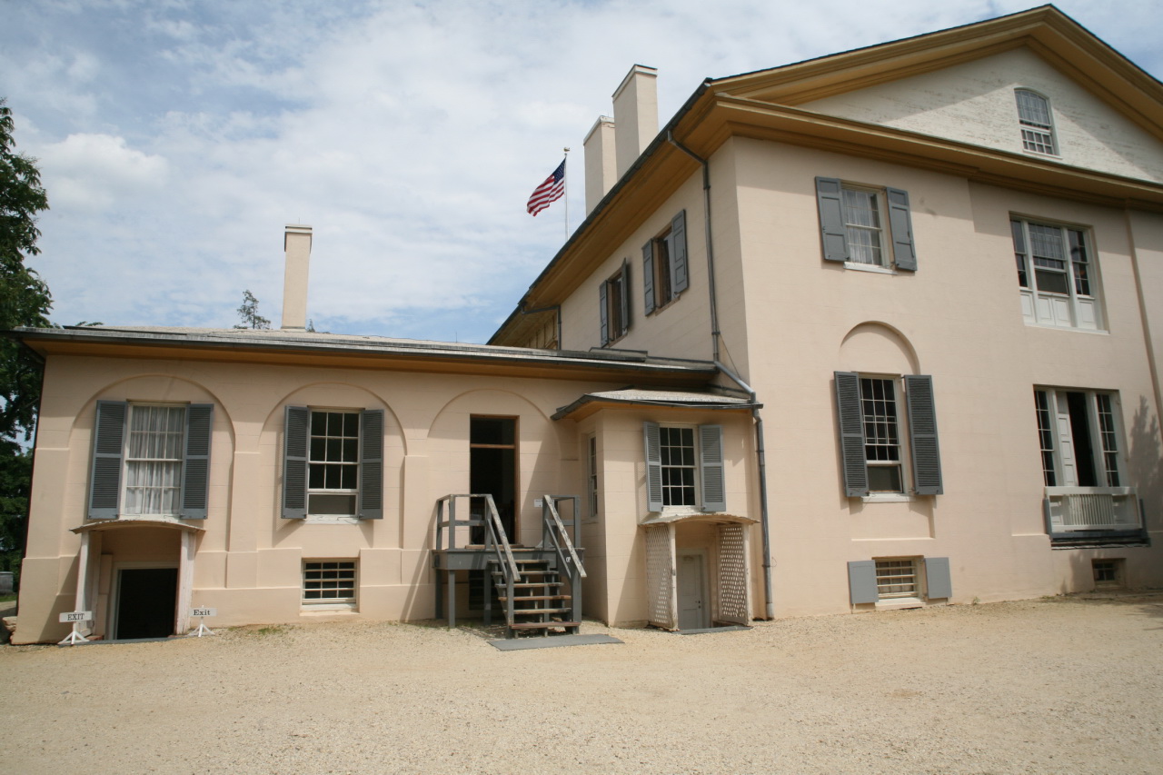 an old white house with a stairway going up and to it's windows