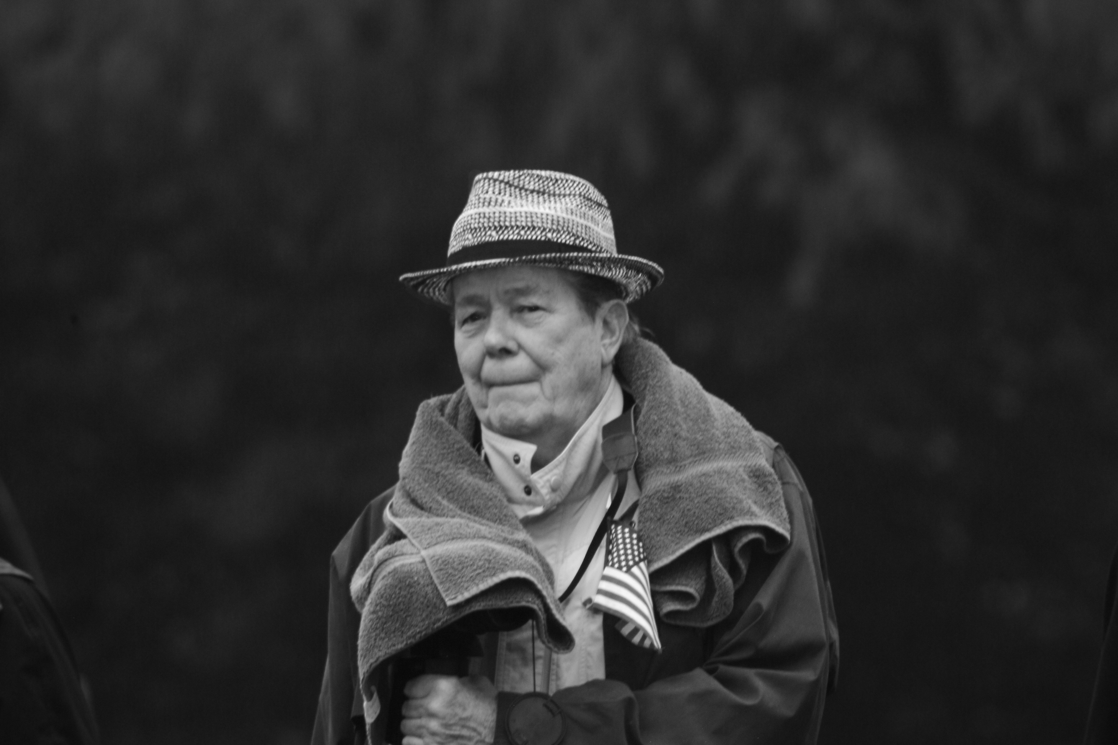 old woman wearing a jacket and hat with flag on it