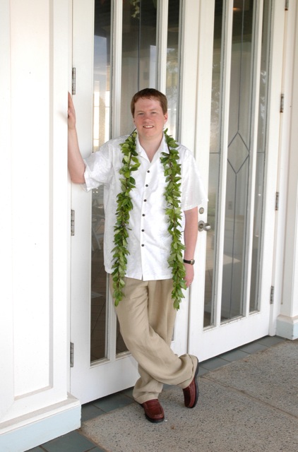 a man stands in front of a door while holding onto a green garland
