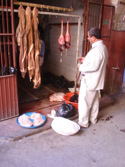 a man in white coat next to a bunch of meat