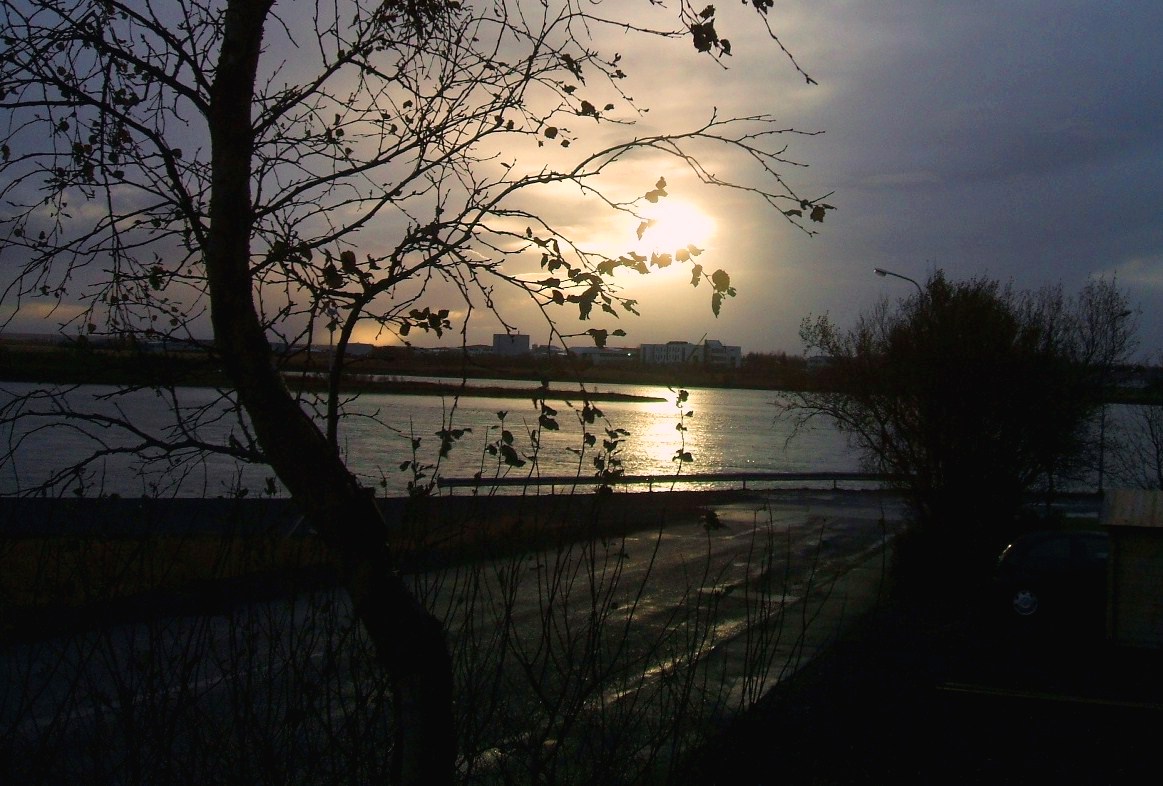 the sun is setting over a river, looking west