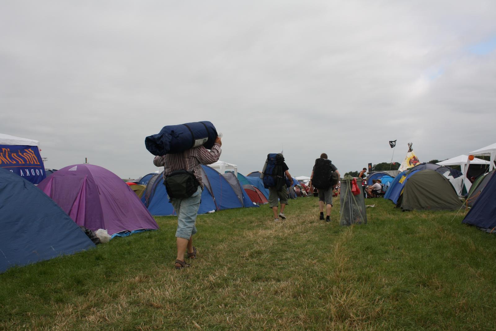 a person walking near tents on a grassy field