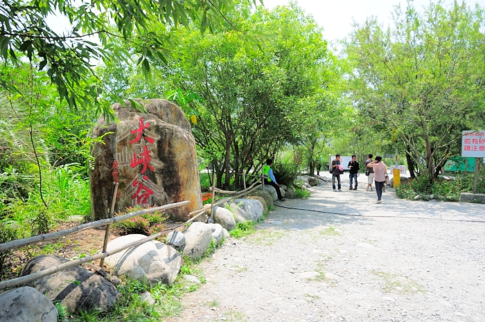 people walking past an area with trees and rocks