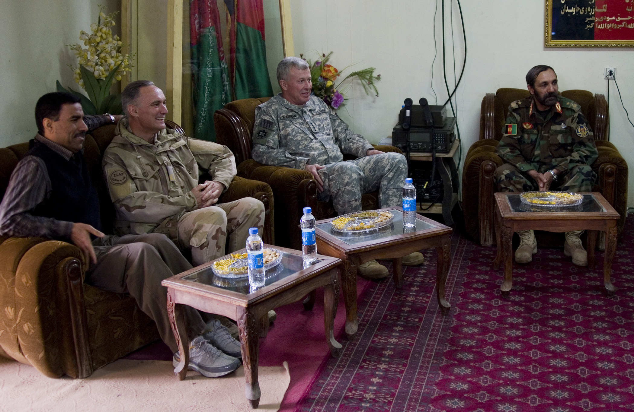 five men sitting in chairs in a living room