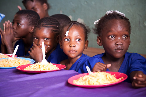 four children at a table eating spaghetti together