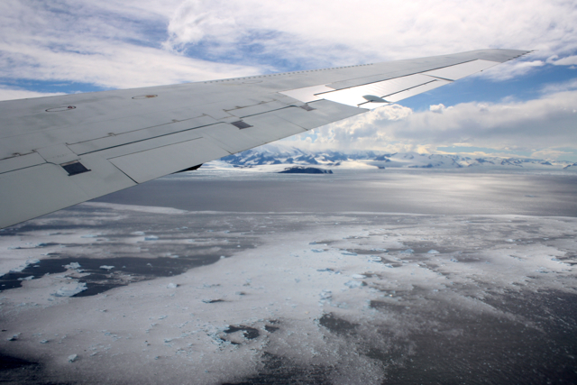 an airplane wing over a frozen lake covered in ice