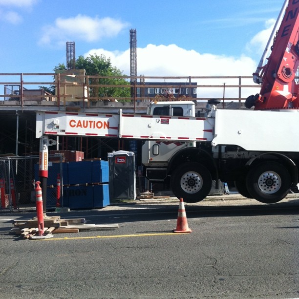 a white truck with a crane is sitting in front of a building