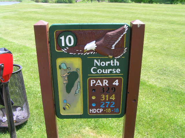 sign out side in a green field with golf tees