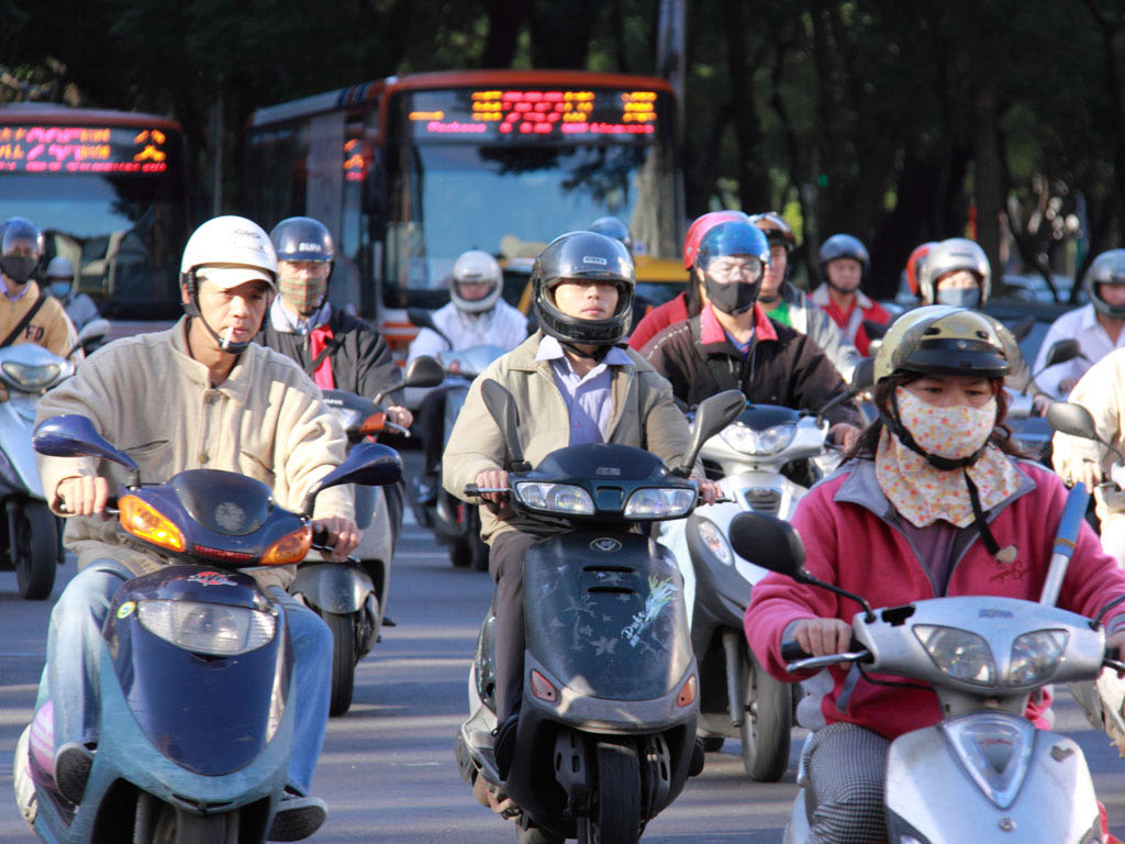 a big group of people on scooters riding down the street