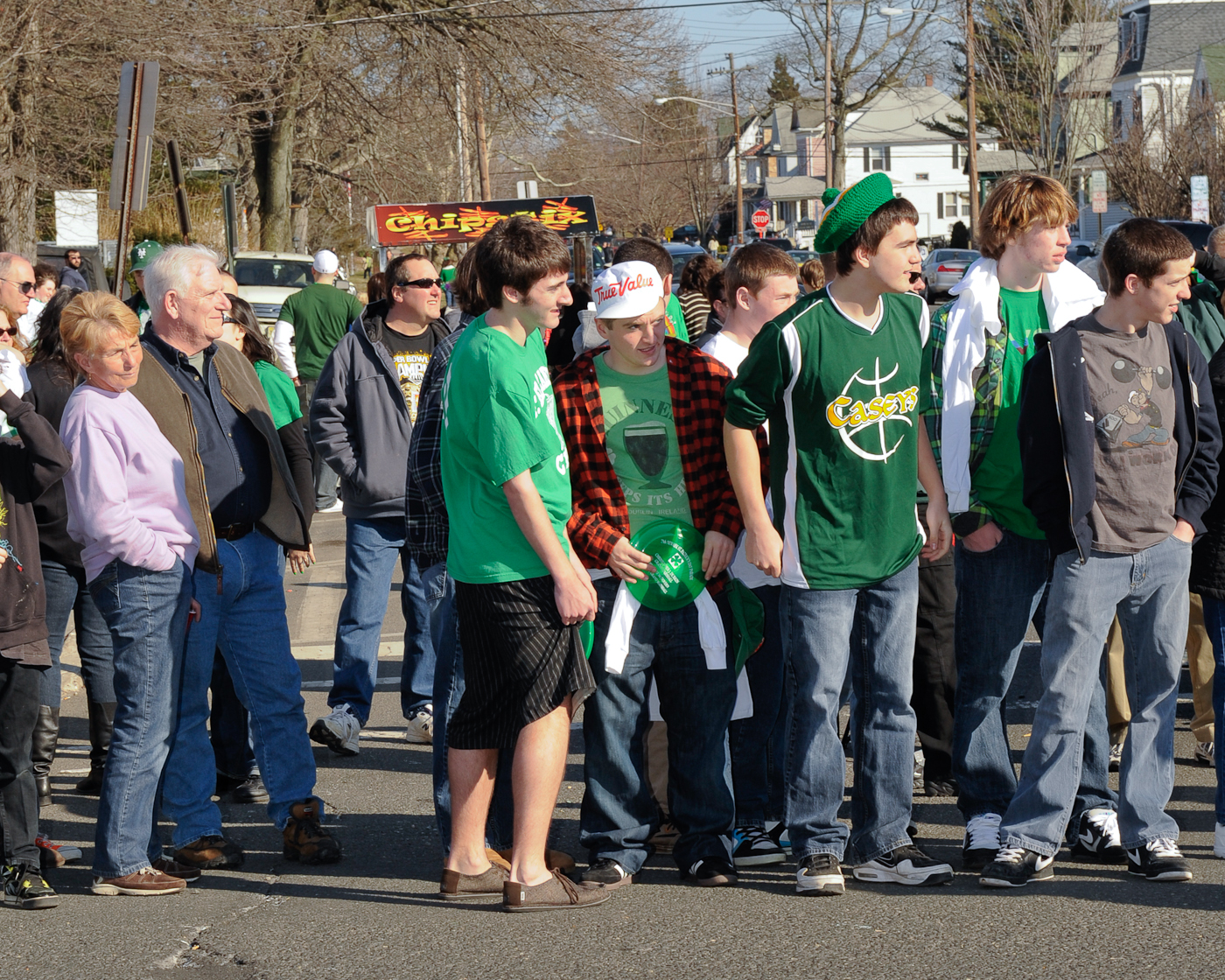 boys in green shirts are standing near some other people
