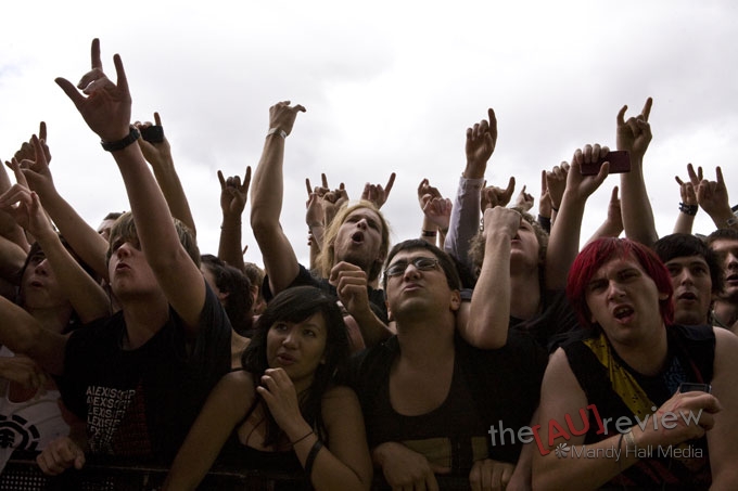 a crowd of people at an outdoor concert with their hands raised