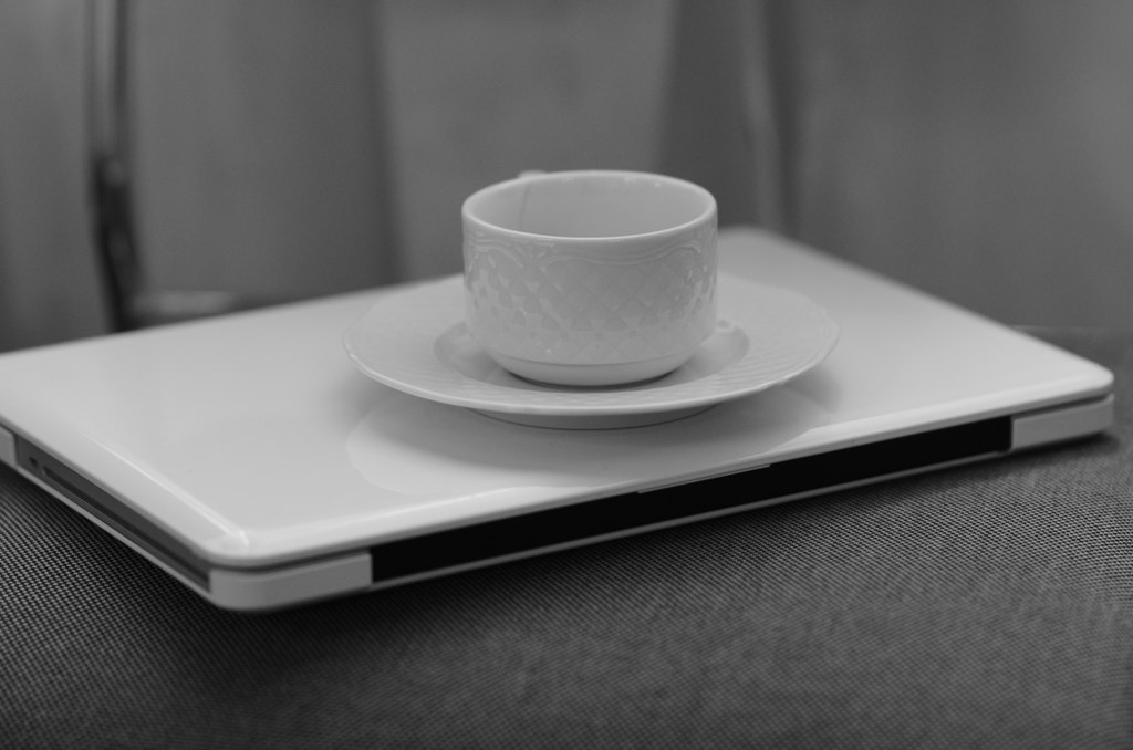 black and white pograph of cup and saucer on a laptop