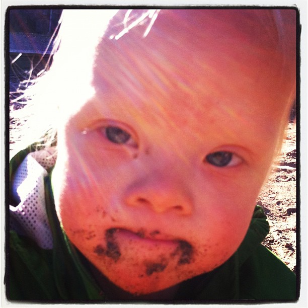 young child making a funny face with a messy dough mixture on his face