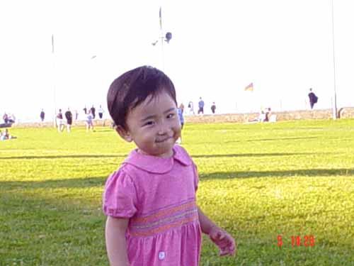 little asian girl standing on a green field